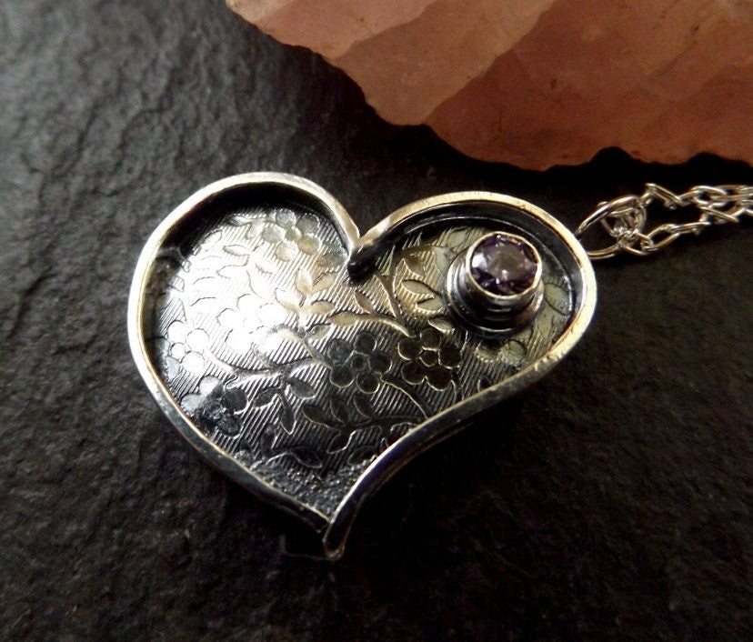 Silver heart necklace with purple cz and flower textured background