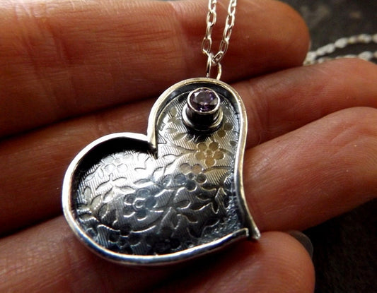 Silver heart necklace with purple cz and flower textured background