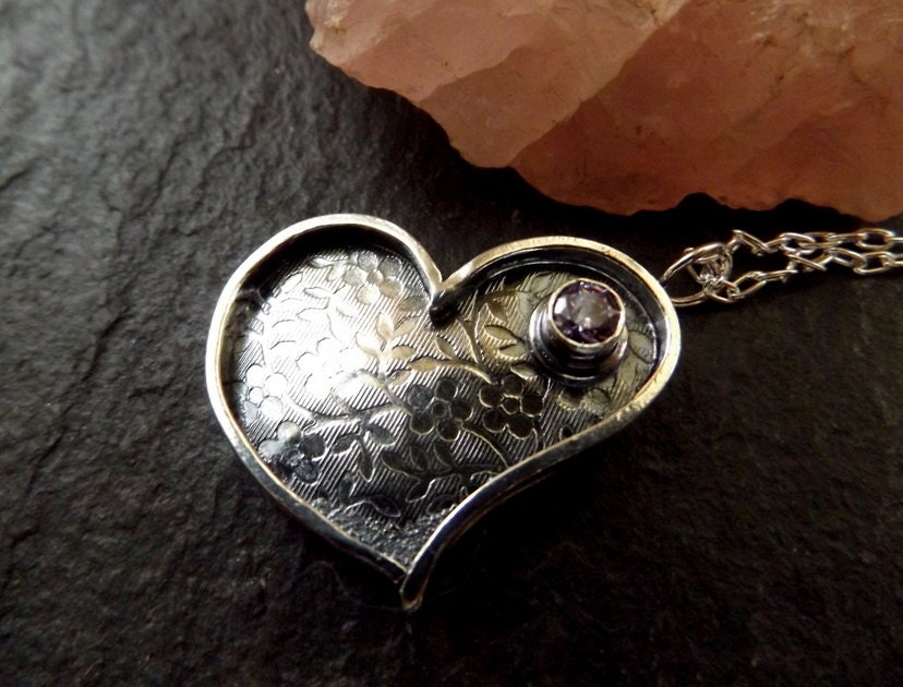 Silver heart necklace with purple cz and flower textured background